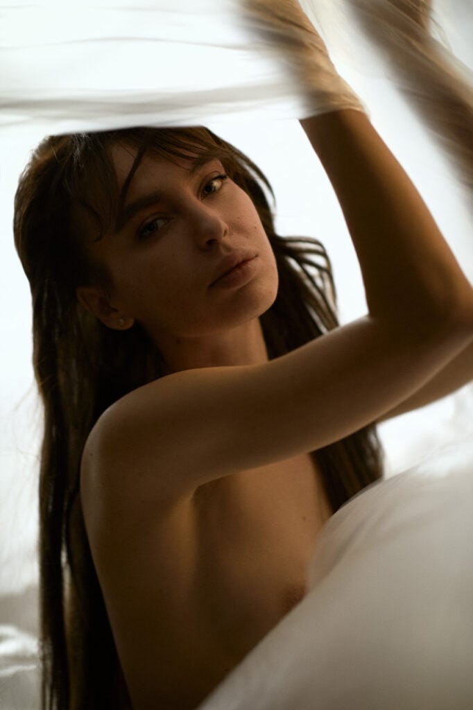 Professionelle Nude Fotografie im Studio München, intimes Schwarz-Weiß Porträt einer Frau mit weißem Laken.
