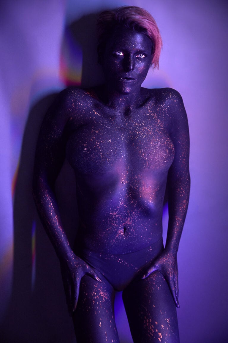 Künstlerisches Bodypainting in Blau und Violett mit goldenen Farbsprenkeln