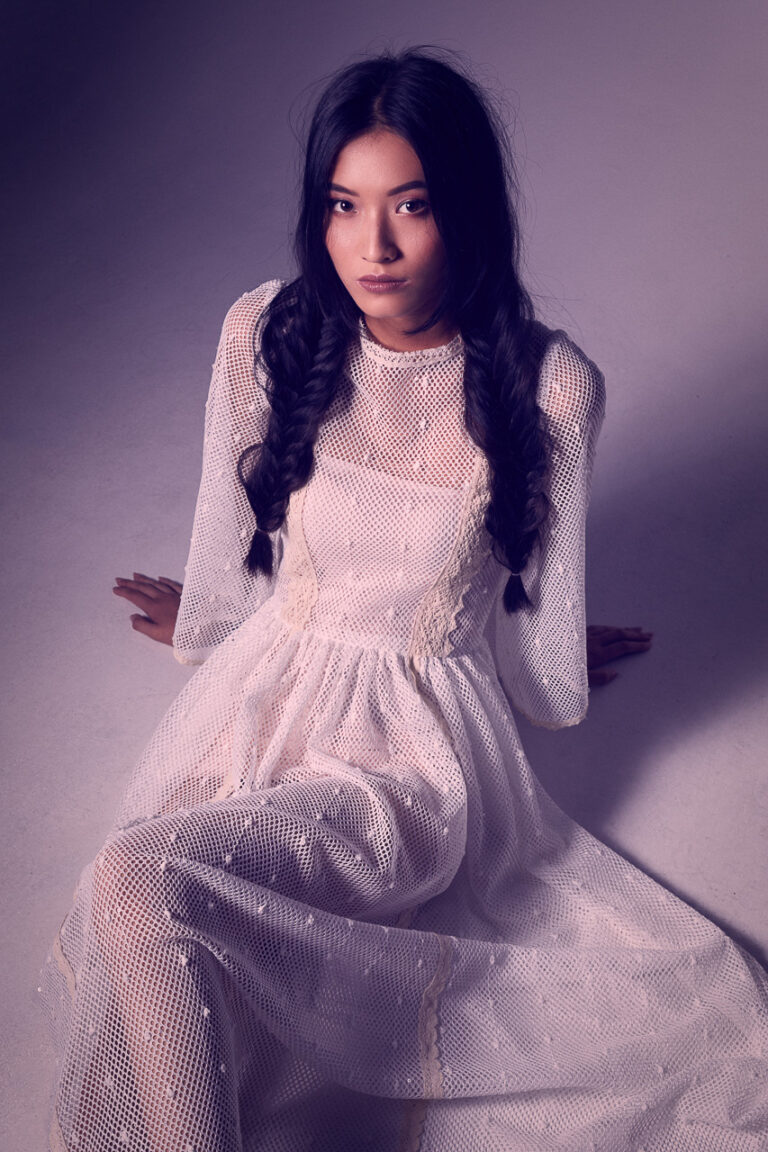 Fashion-Porträt einer Frau in langem weißem Spitzenkleid mit geflochtenen Zöpfen