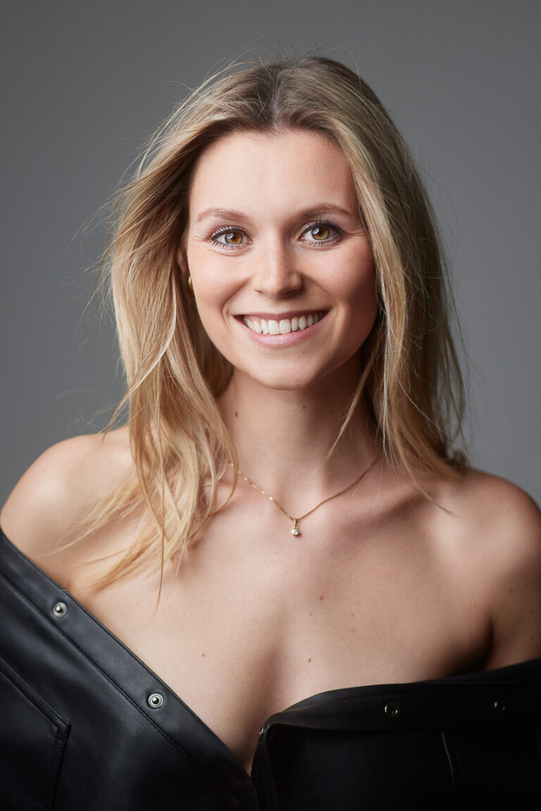 Natürliches Beauty-Portrait einer lächelnden jungen Frau vor grauem Hintergrund